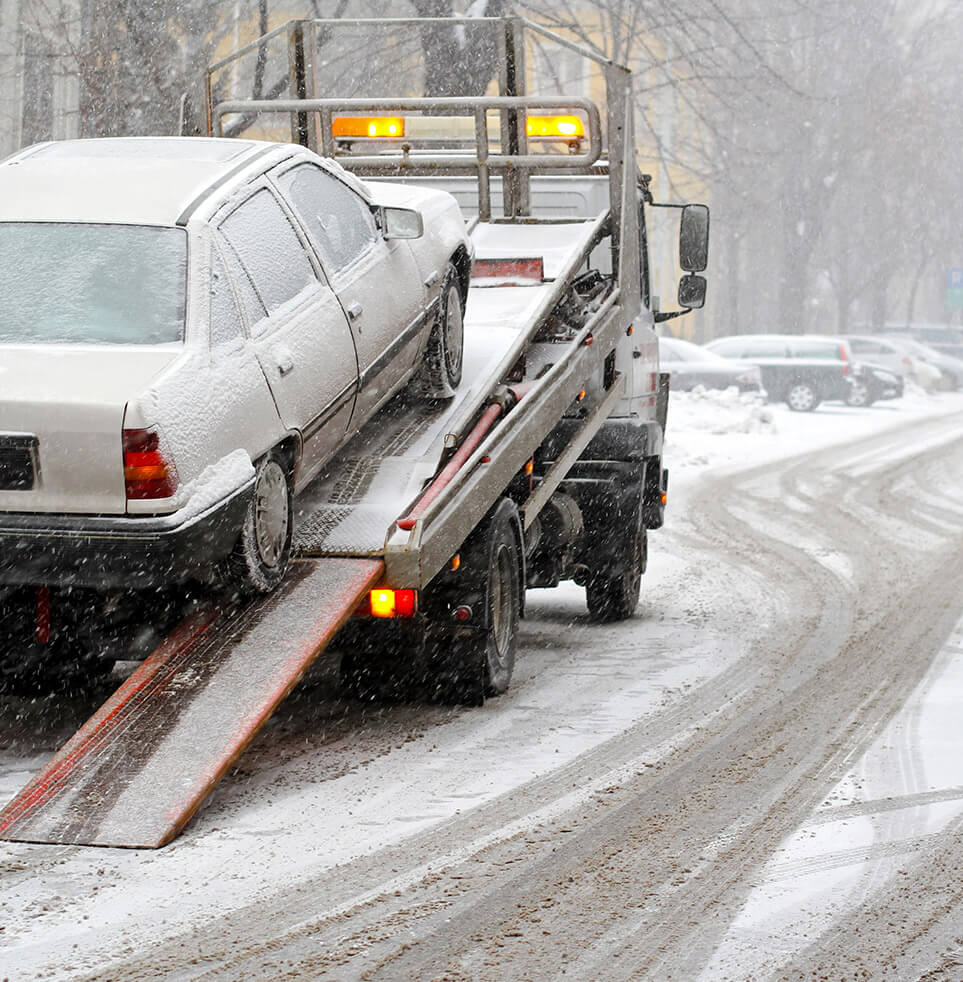 Flatbed towing a vehicle in winter conditions